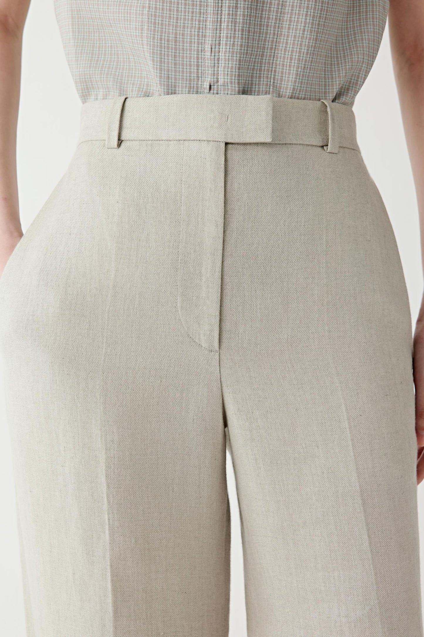 Close-up of the waistband and front fastening detailing the fitted construction, belt loops and concealed closure. The image highlights the compact twill weave and subtle texture of the fabric surface.