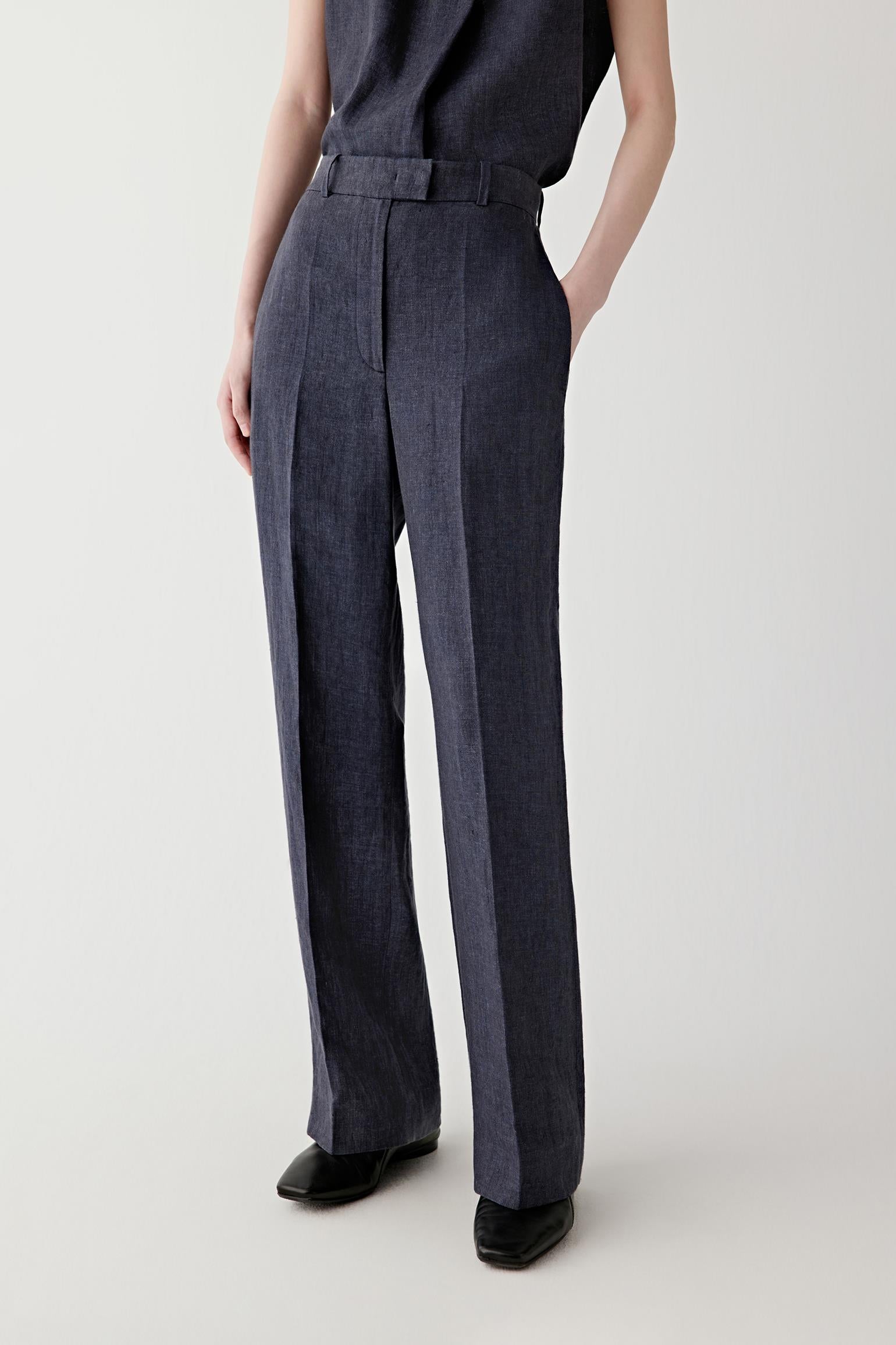 Front view of a woman wearing indigo blue straight-leg trousers in linen, highlighting the dry textured surface, softly structured drape and subtle tonal depth of the woven fabric.