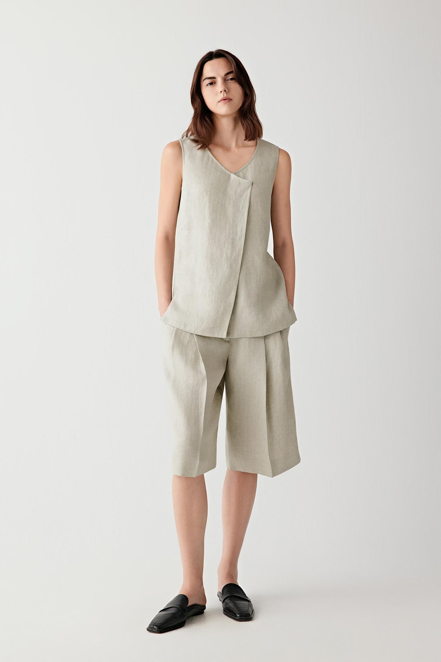 Full-length front view showing the relaxed silhouette, fitted waistband and elongated proportions. Front pleats create soft volume while maintaining clean lines through the shorts.