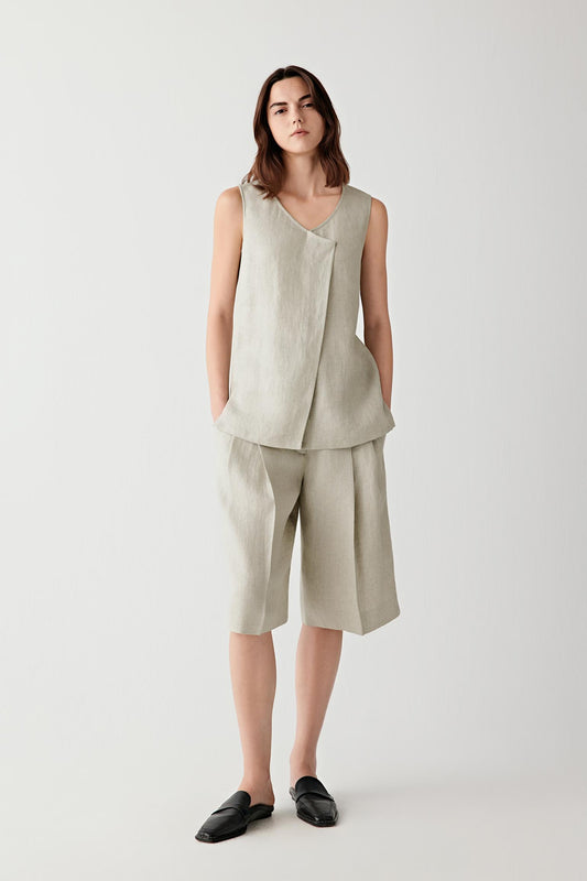 Full-length front view showing the relaxed silhouette, fitted waistband and elongated proportions. Front pleats create soft volume while maintaining clean lines through the shorts.