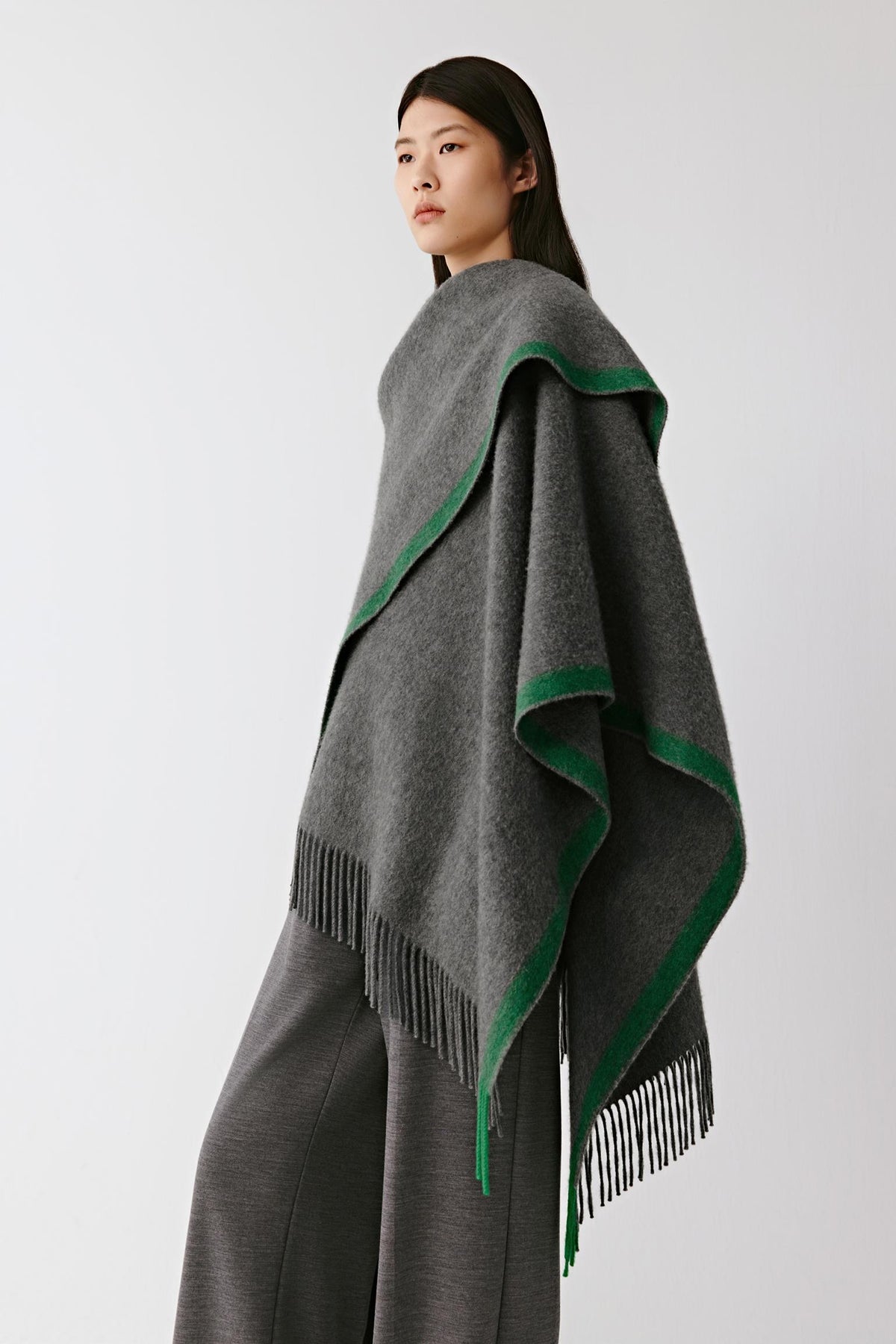 Three-quarter view showing the drape and contrasting green edges of the grey cashmere shawl.