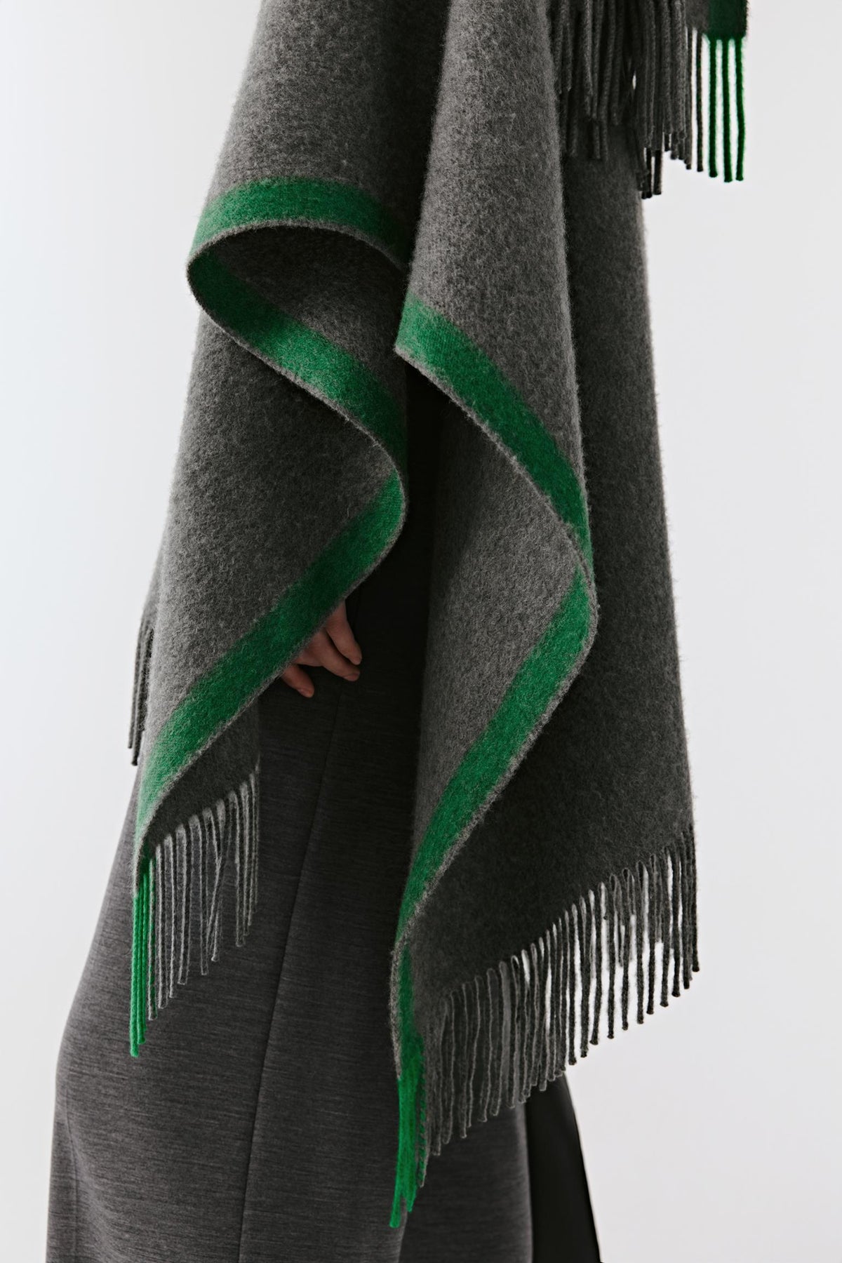 Close-up highlighting the contrasting green edging and fringed trims of the grey cashmere shawl.
