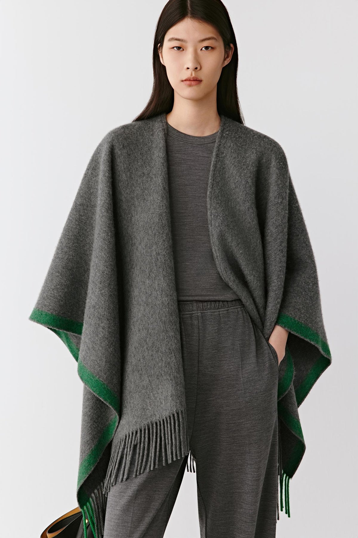 Front view highlighting the open silhouette and drape of the grey cashmere shawl with green edging.