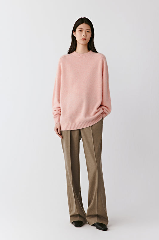 Full-length front view of the model wearing the heathered pink cashmere jumper with loose brown trousers, showing its soft and lightweight drape.
