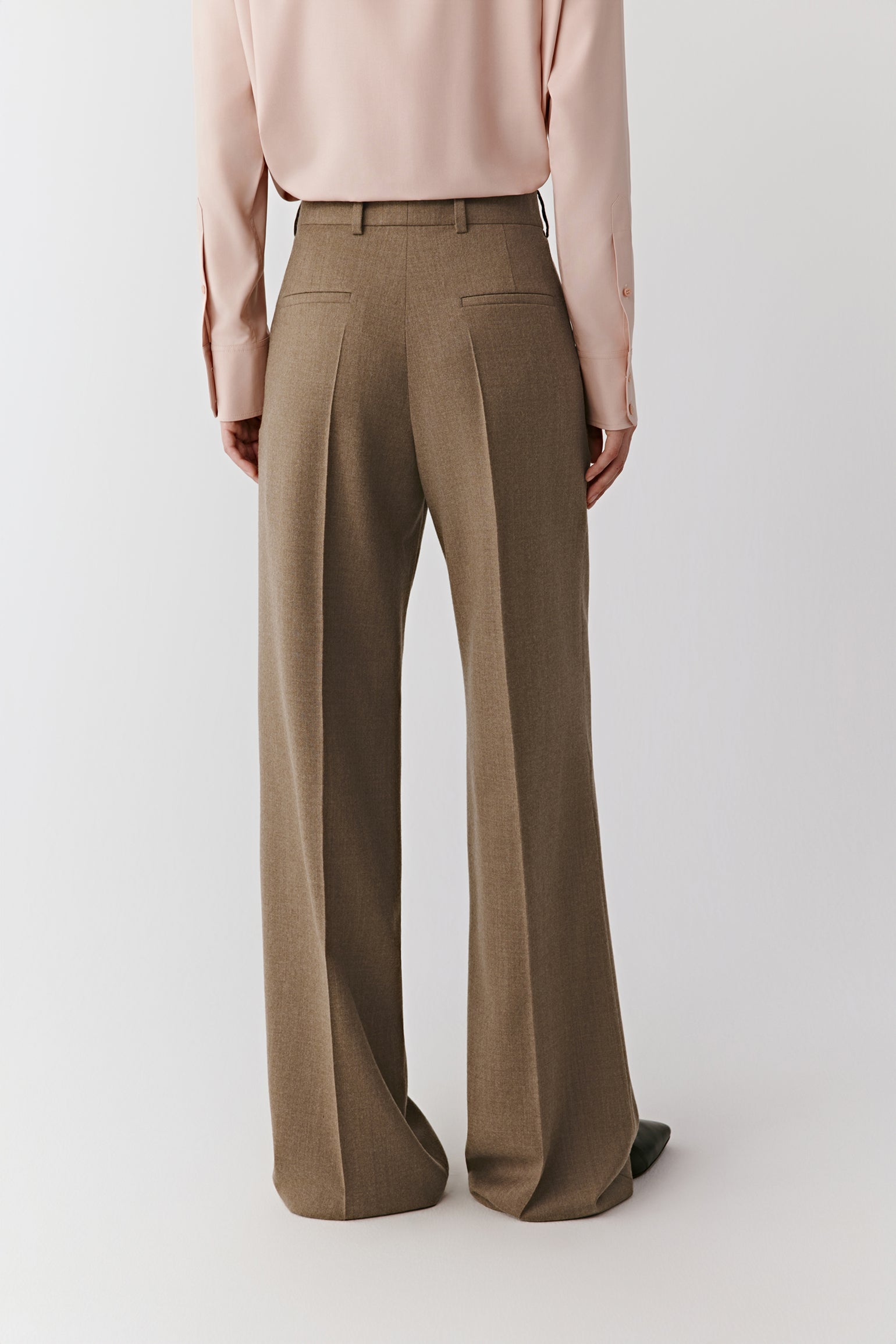 Back view showing the structured silhouette with welt pockets and smooth finish