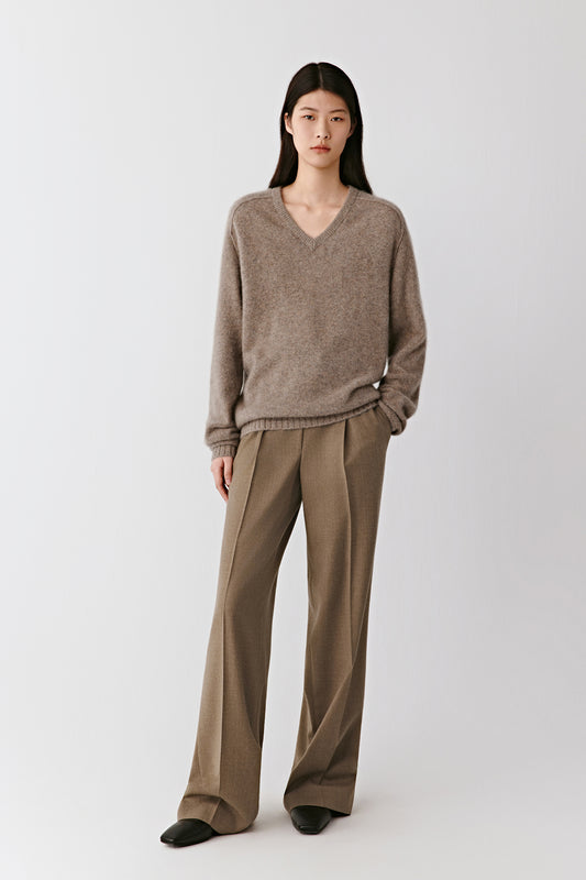 Full-length front view of the model wearing the brown mélange cashmere sweater with wide trousers, showing its relaxed and elegant silhouette.