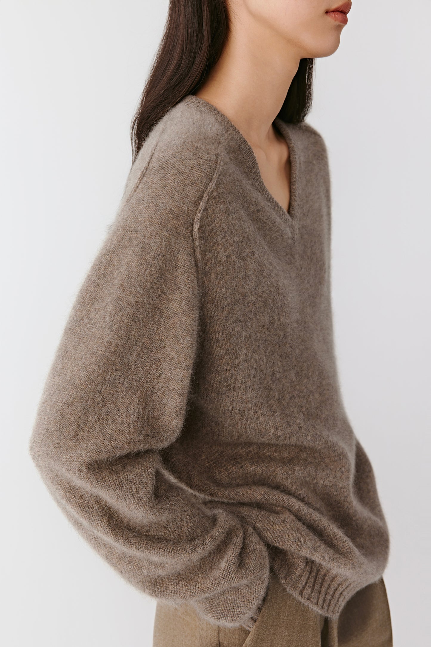 Side view showing the light drape and ribbed trims at the hem and cuffs.