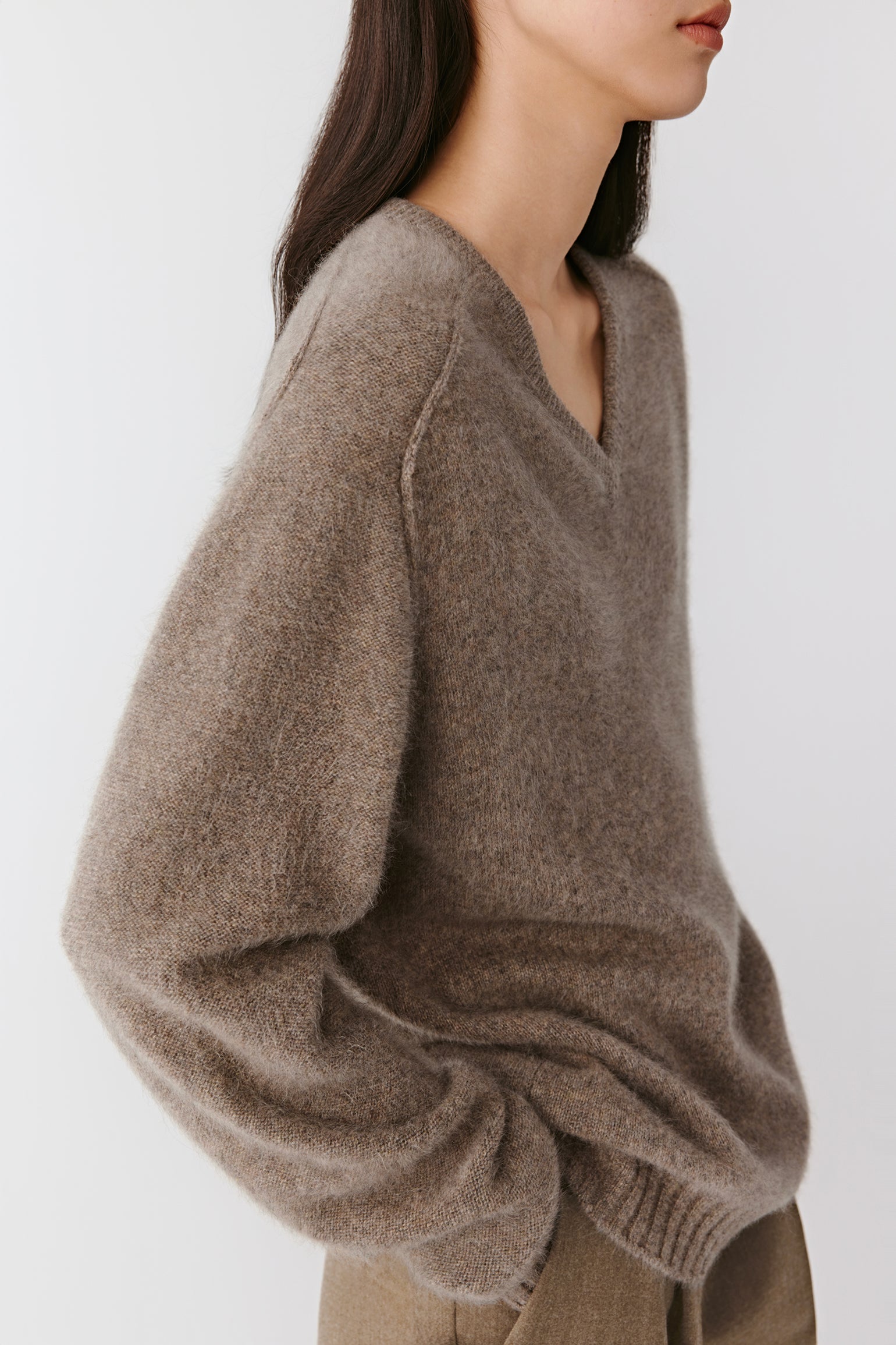 Side view showing the light drape and ribbed trims at the hem and cuffs.