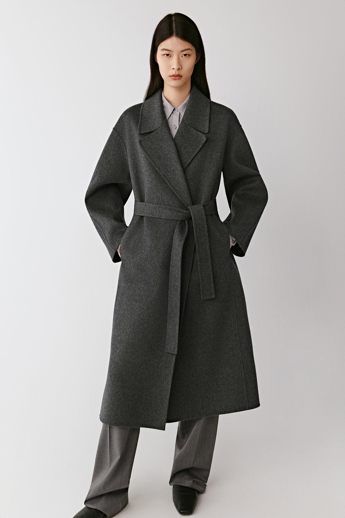 Full-length front view of the model wearing the grey double-faced cashmere coat, showing its relaxed cut and enveloping softness.