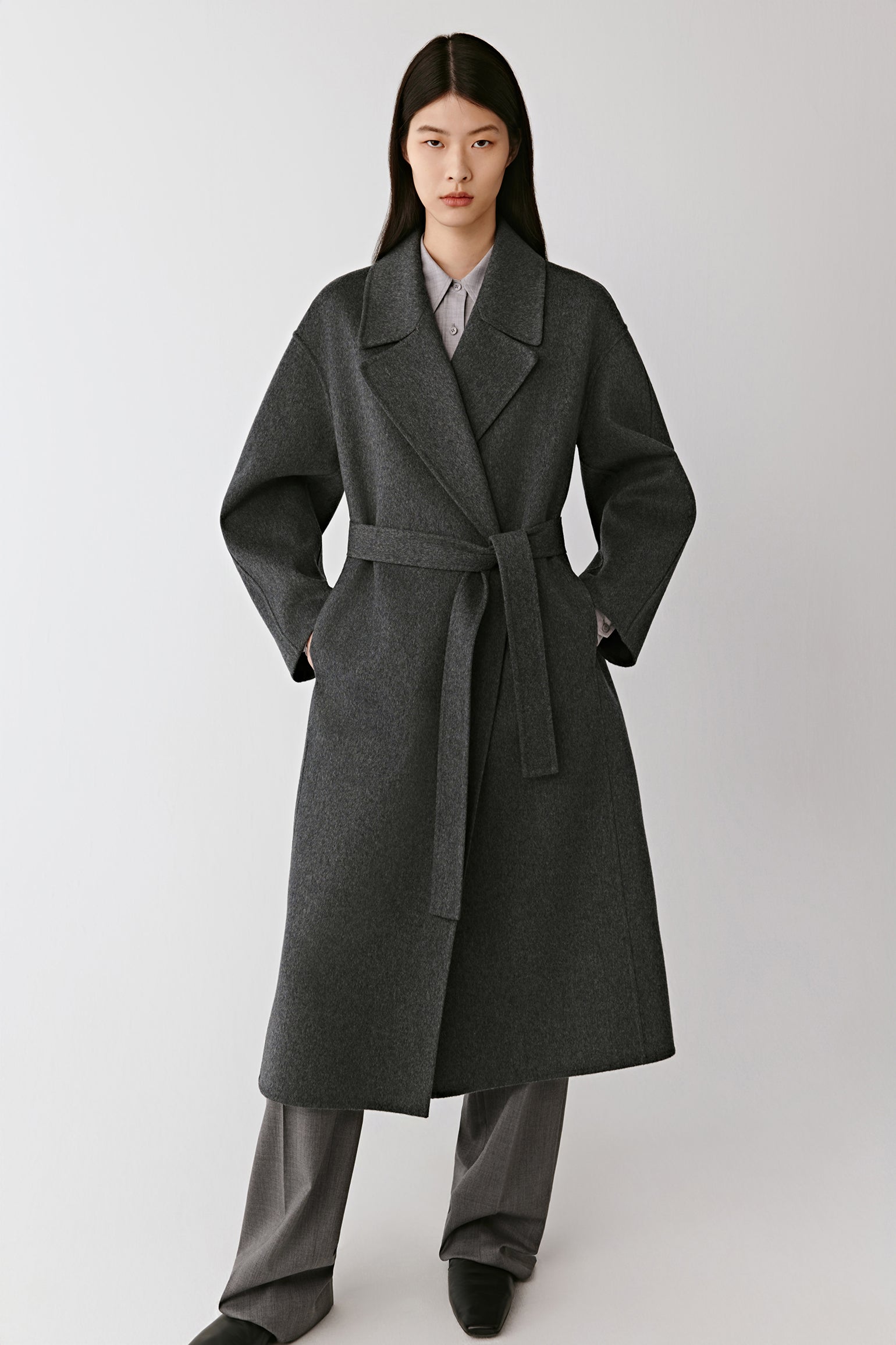 Full-length front view of the model wearing the grey double-faced cashmere coat, showing its relaxed cut and enveloping softness.