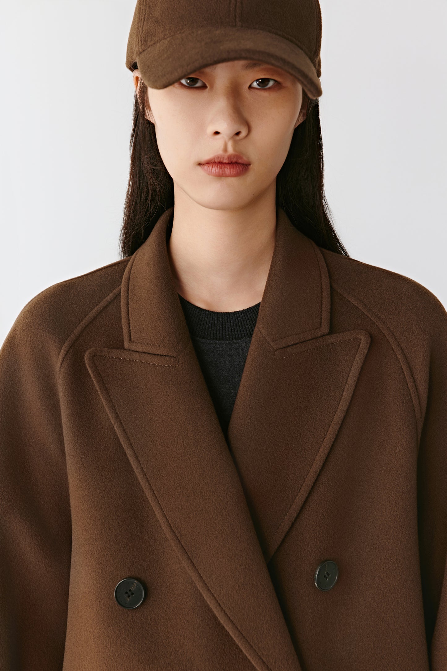 Front view showing the neckline and natural structure of the coat, paired with a cap.