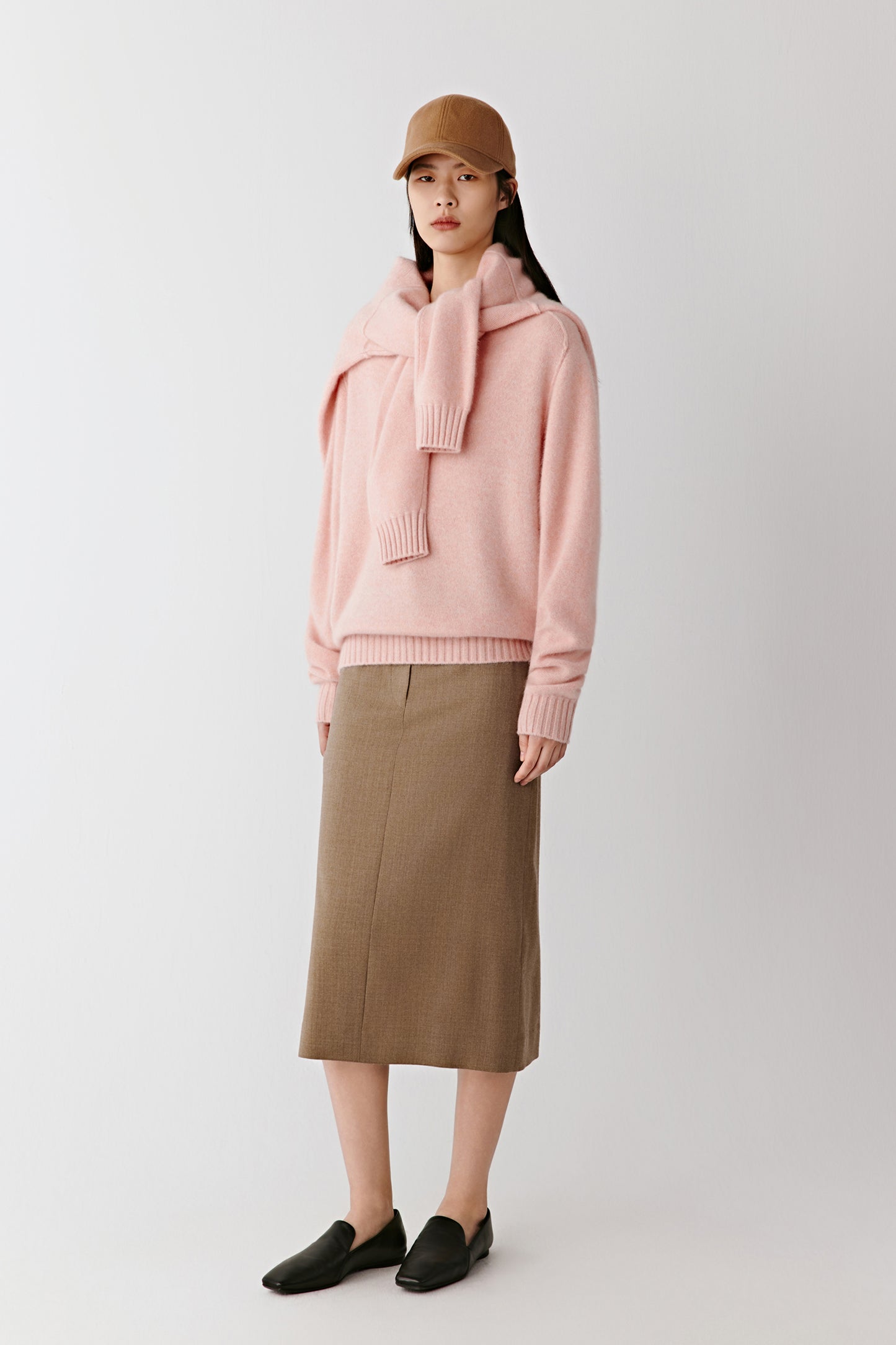 The model is captured in a relaxed stance, highlighting the jumper’s fluid drape and heathered pink tone.