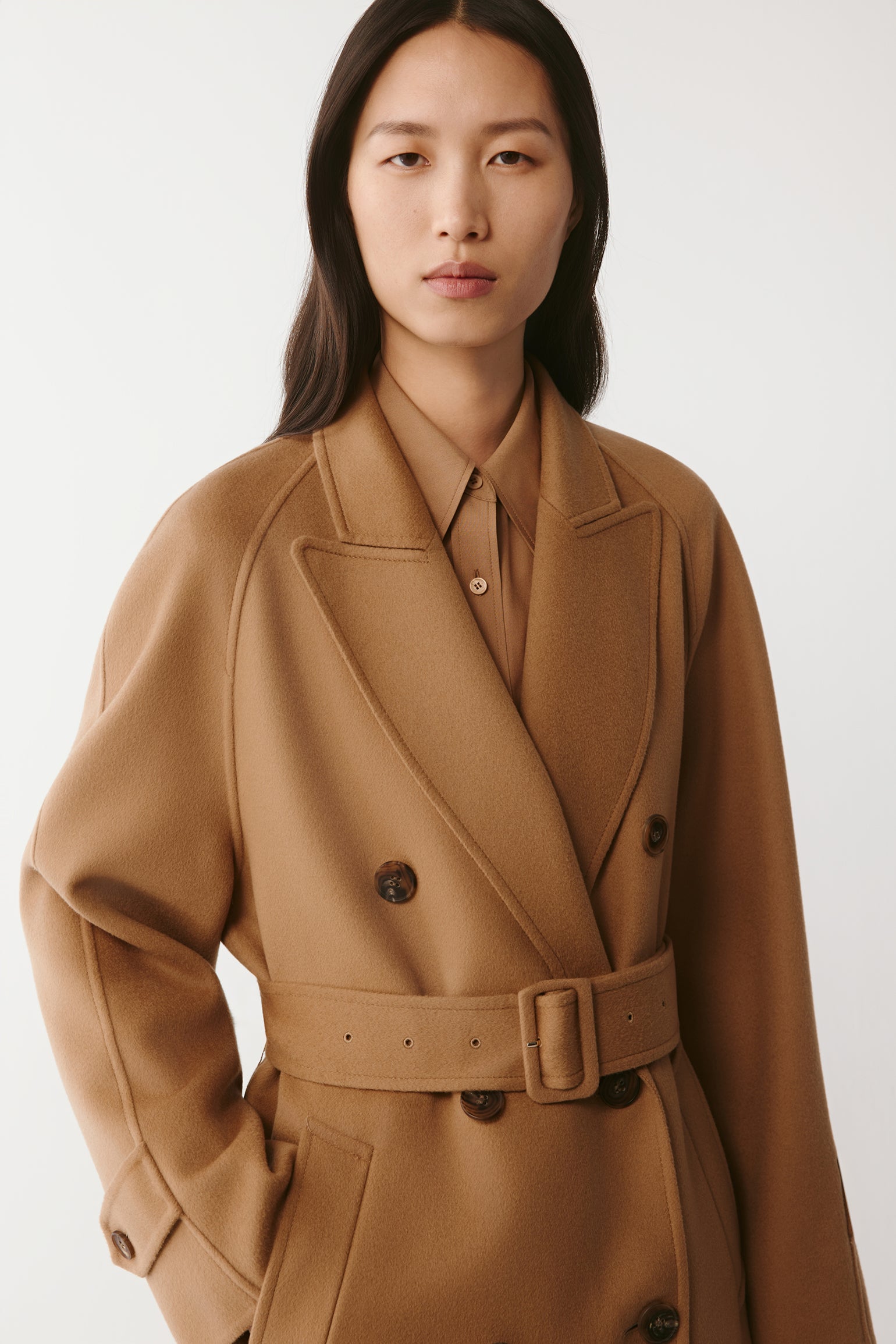 Three-quarter front view emphasizing the double-breasted closure and belt detail.