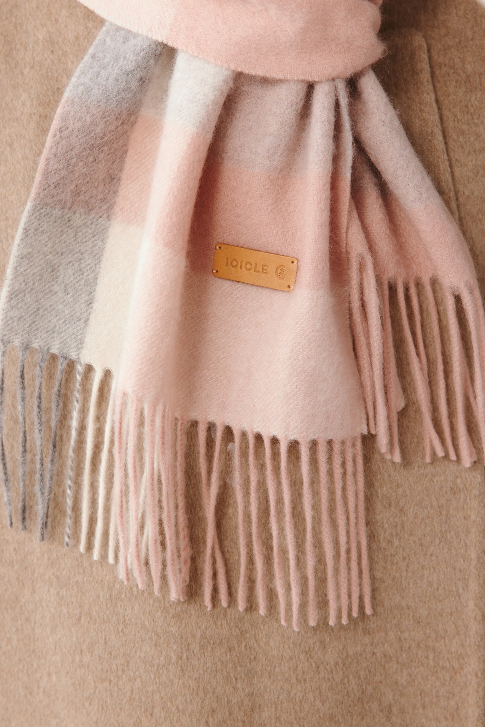 A detailed view of the pink checked cashmere scarf, highlighting the woven pattern and delicate fringed ends.