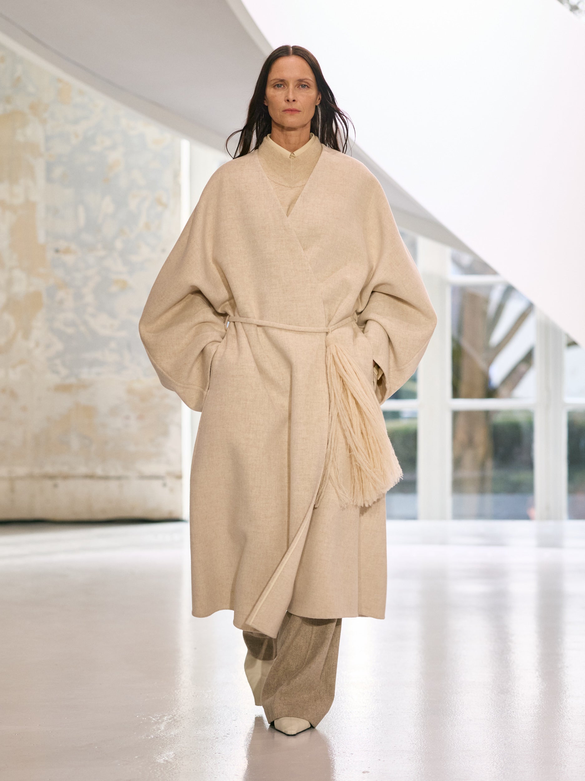 Woman wearing a beige outfit in a minimalistic indoor setting