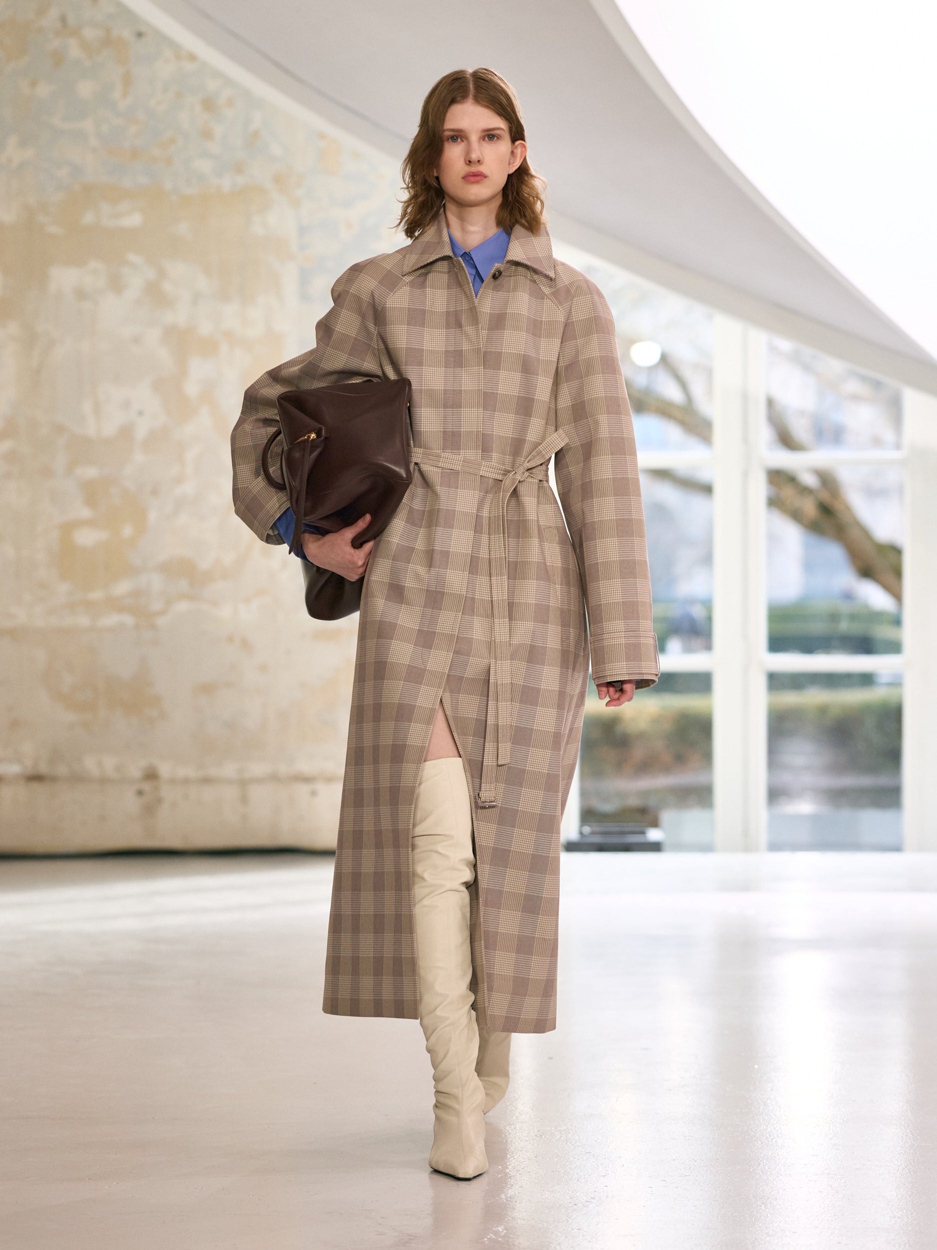 Model wearing a plaid coat with a blurred indoor background