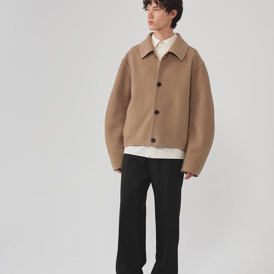 Video of a man wearing a camel melange double-face wool coat, showing the movement of the relaxed silhouette and dense wool fabric as he moves.