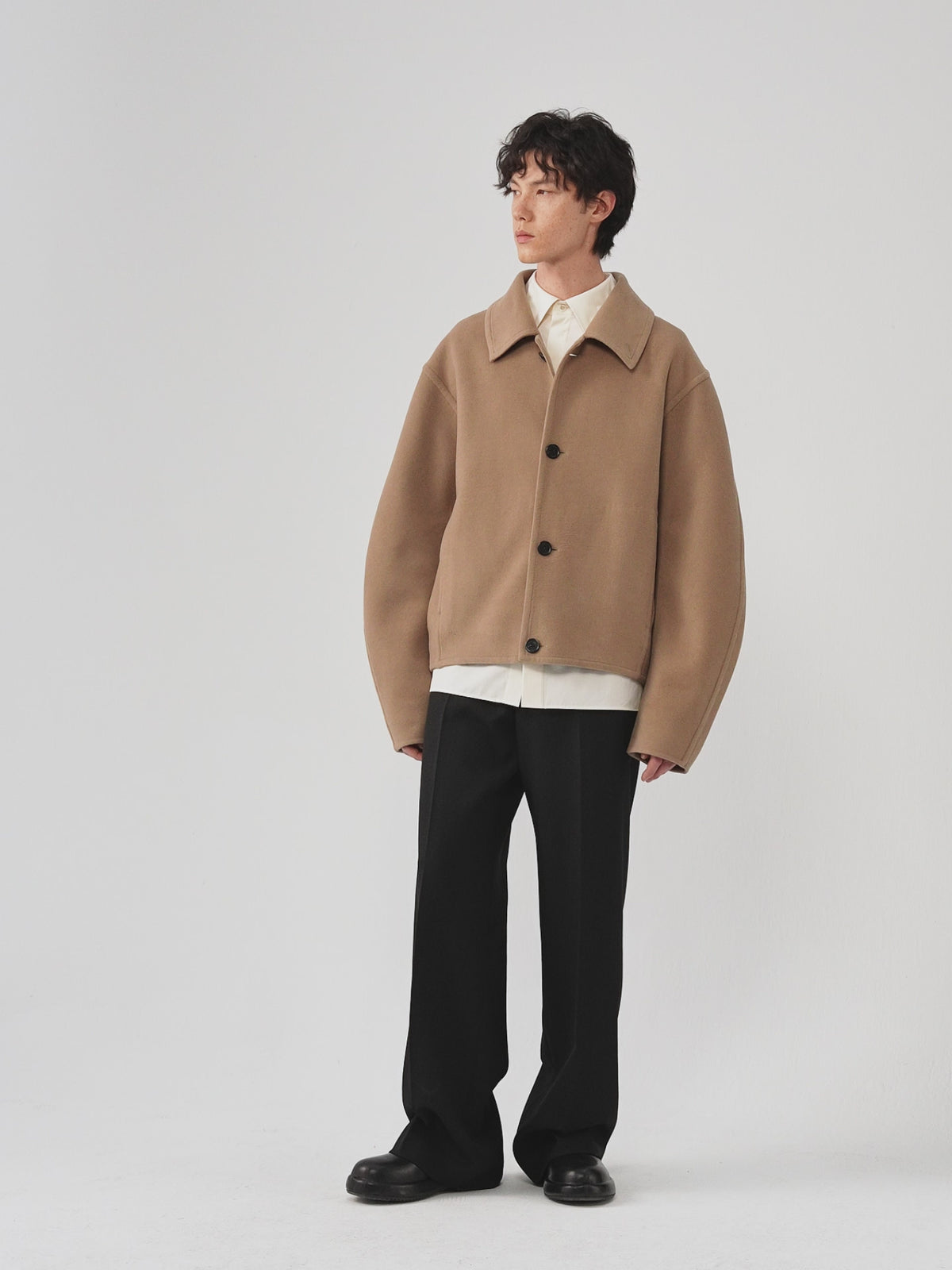 Video of a man wearing a camel melange double-face wool coat, showing the movement of the relaxed silhouette and dense wool fabric as he moves.