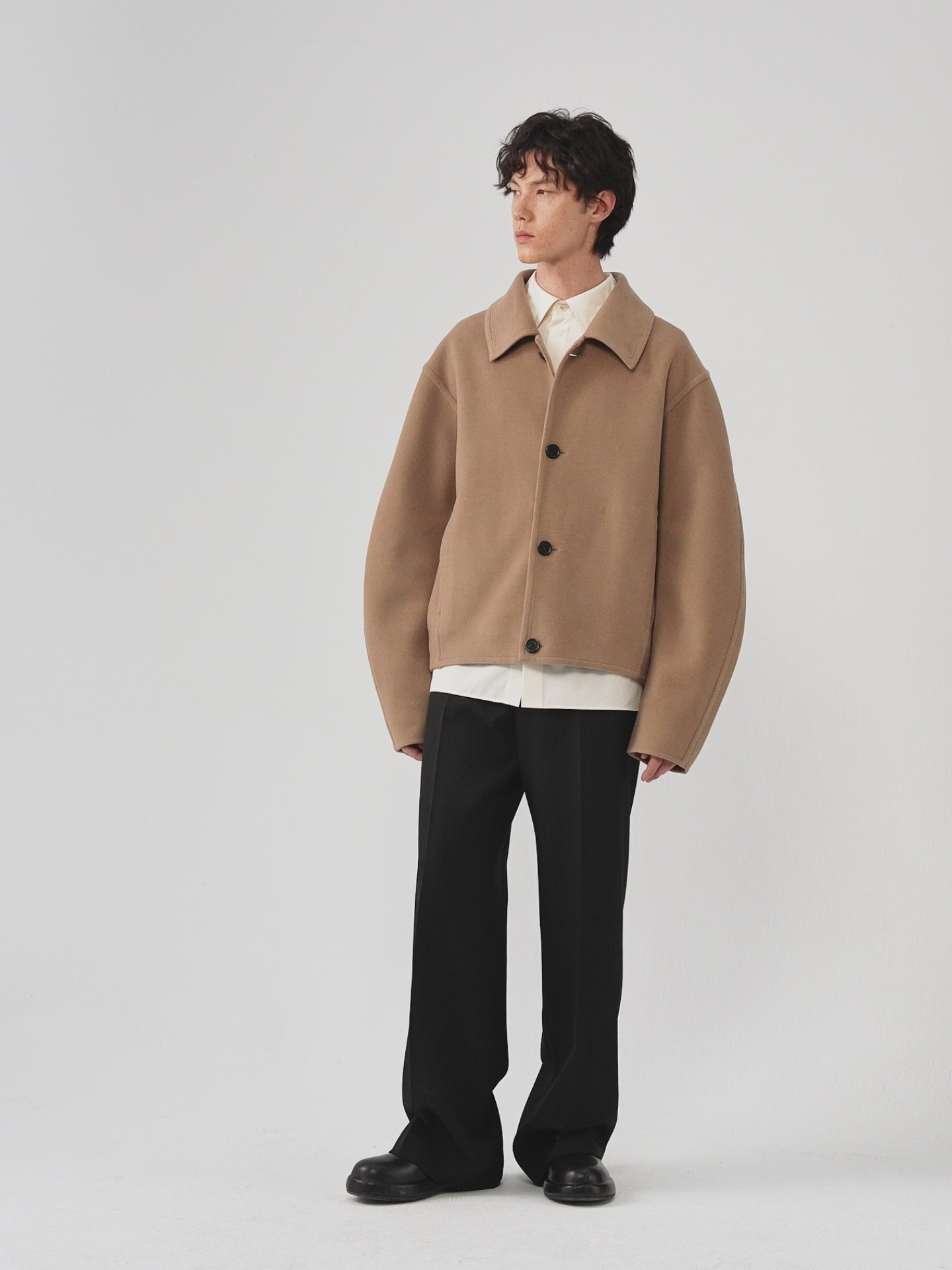 Video of a man wearing a camel melange double-face wool coat, showing the movement of the relaxed silhouette and dense wool fabric as he moves.