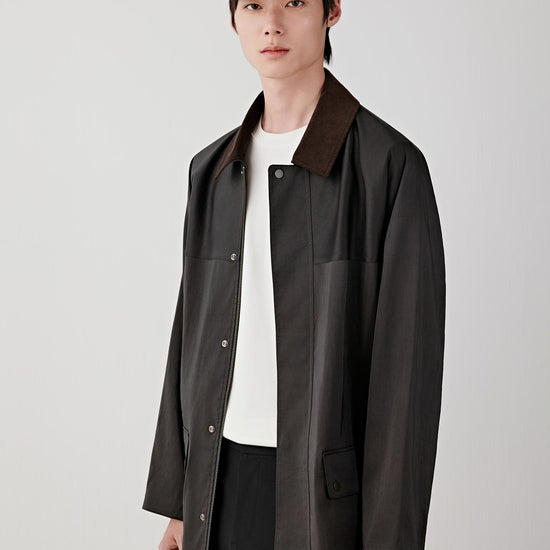 Man wearing a deep black Gambiered Canton gauze silk jacket with a straight, relaxed cut and classic collar, styled with matching trousers. He moves through front, three-quarter and side views, showing the lightweight structure, fluid drape and naturally textured surface of the silk. The fabric shifts with light, revealing a subtle sheen and depth from the dyeing process, while the clean lines, concealed fastening and relaxed fit remain consistent throughout.