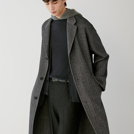 Video Front view of a man wearing a grey herringbone wool and cashmere coat, showing the relaxed silhouette, notched lapels and long length.