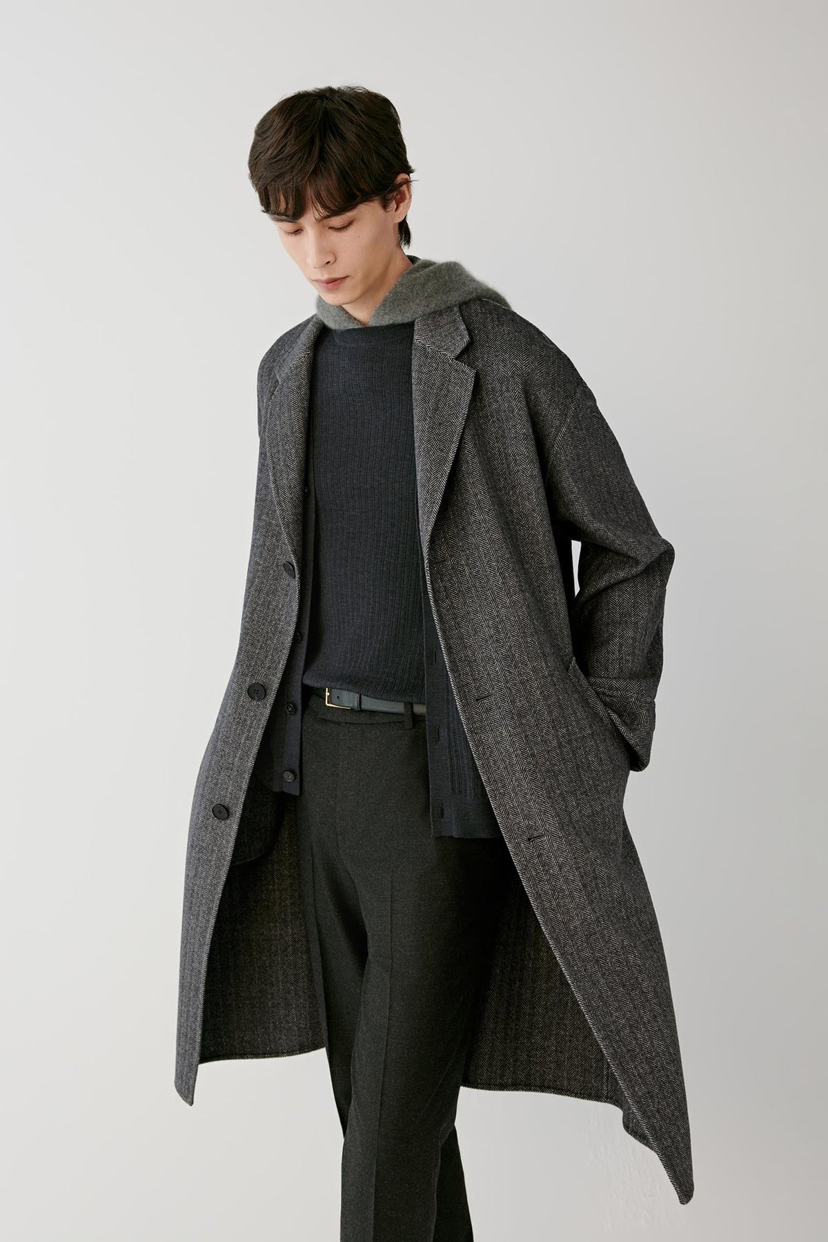 Video Front view of a man wearing a grey herringbone wool and cashmere coat, showing the relaxed silhouette, notched lapels and long length.