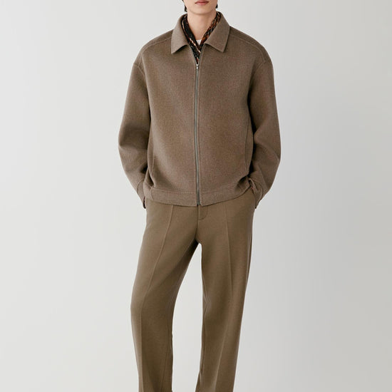 Video Front view of a man wearing a brown melange cashmere jacket, showing the relaxed silhouette, pointed collar and front zip fastening.
