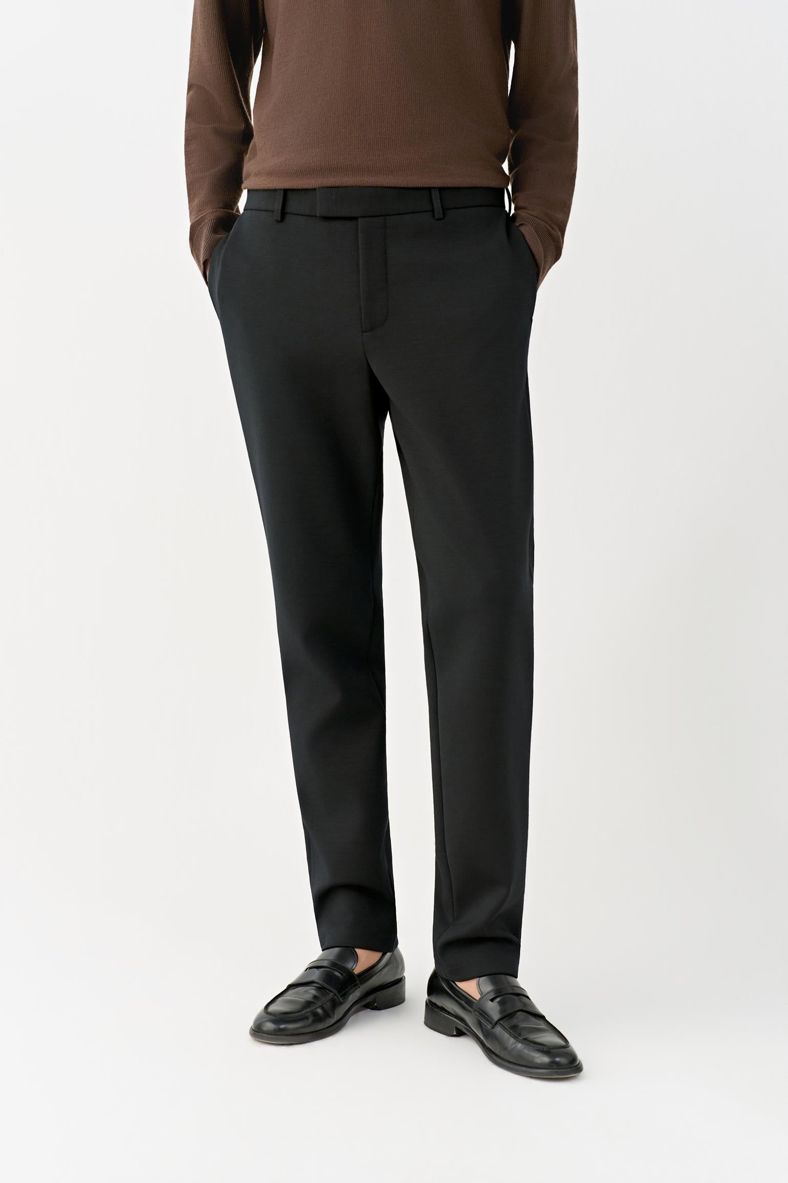 Video Front view of a man wearing deep black slim-leg wool trousers, showing the streamlined silhouette and mid-rise waist.