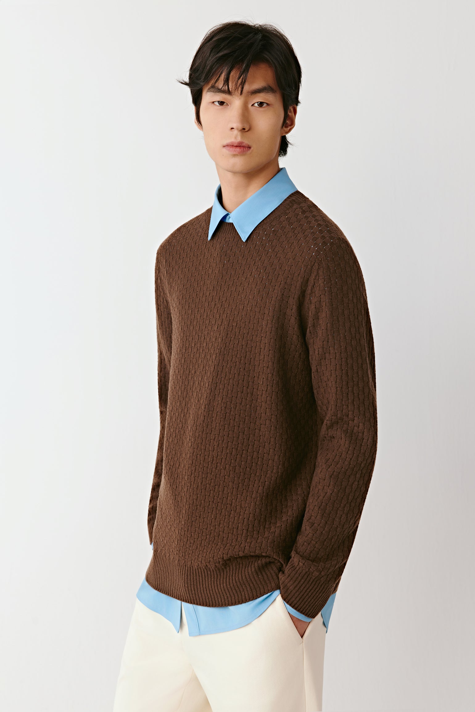 Product video showing a brown wool pullover worn with light trousers, rotating to display the fit, knit texture, neckline, sleeves, and overall silhouette from all angles.