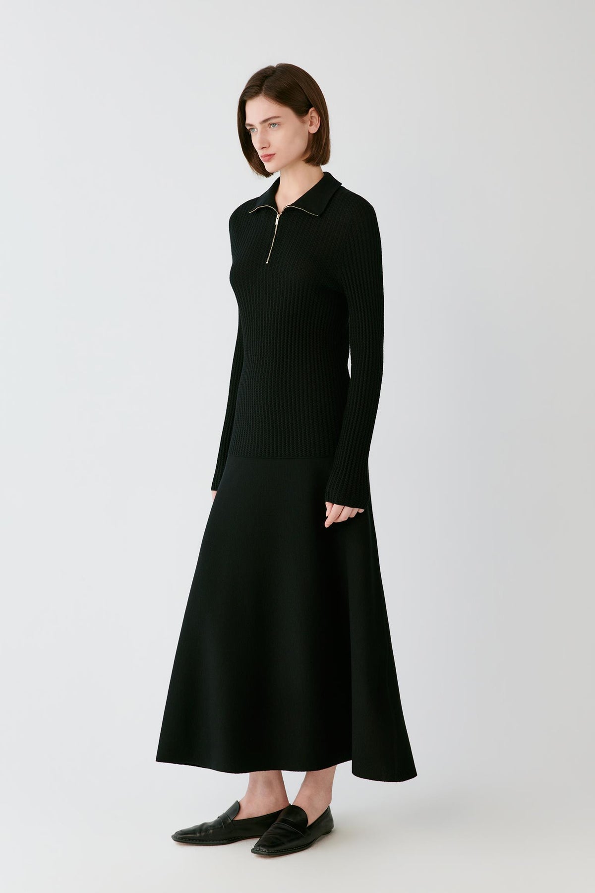 Video Front full-length view of a woman wearing the deep black worsted wool pullover, highlighting the long sleeves and fitted silhouette.