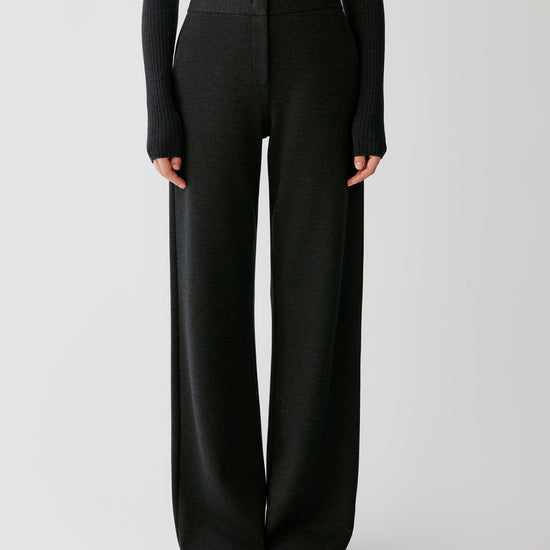 Video of a woman wearing dark grey melange blended jersey trousers, showing the straight-leg silhouette and clean waistband.