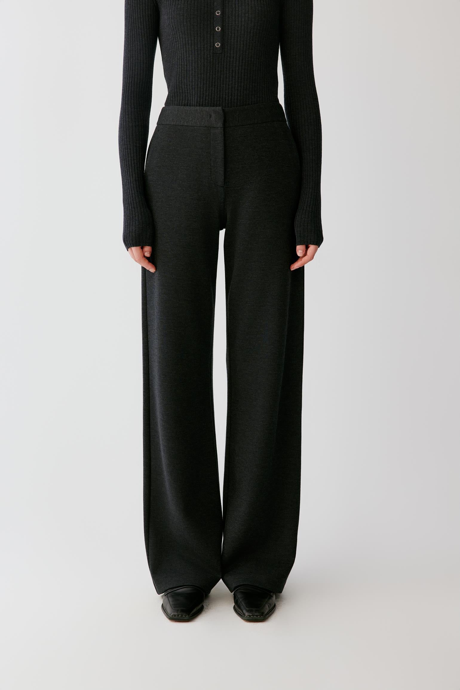 Video of a woman wearing dark grey melange blended jersey trousers, showing the straight-leg silhouette and clean waistband.