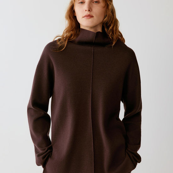Full-length view of a woman wearing the dark brown merino wool pullover, highlighting the straight fit and long sleeves.