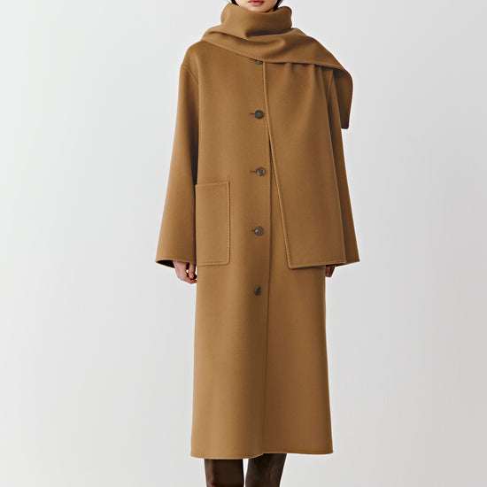 Product video showing a camel straight coat in double-faced wool and cashmere with an integrated scarf, rotating to display the fit, length, scarf detail, pockets, and overall silhouette from all angles.