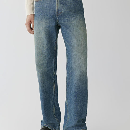 Video Front view of a man wearing blue denim jeans, showing the low-rise waist and loose-leg silhouette.