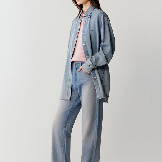 Video showing the model walking in a coordinated denim outfit, emphasizing the fluid movement of the cotton denim shirt, the soft structure through the shoulders and sleeves, and the relaxed silhouette in motion