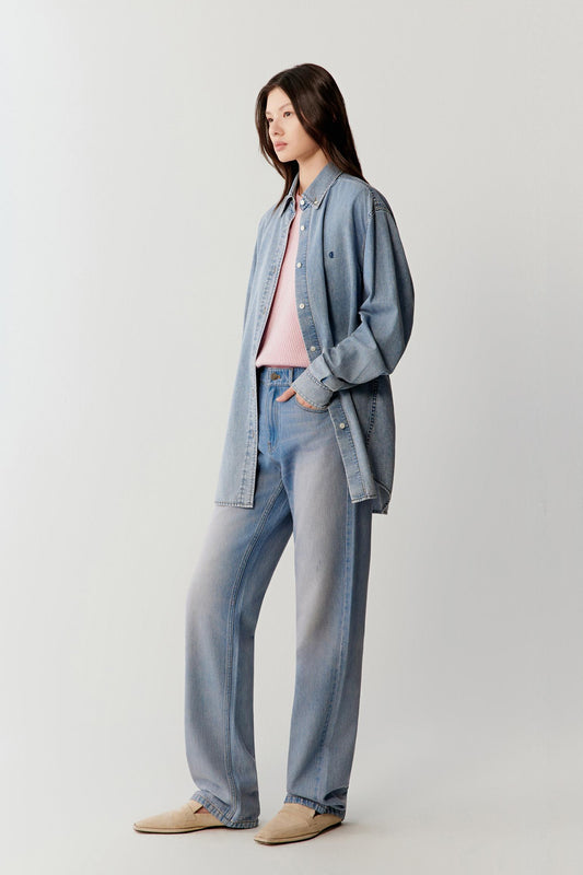 Video showing the model walking in a coordinated denim outfit, emphasizing the fluid movement of the cotton denim shirt, the soft structure through the shoulders and sleeves, and the relaxed silhouette in motion