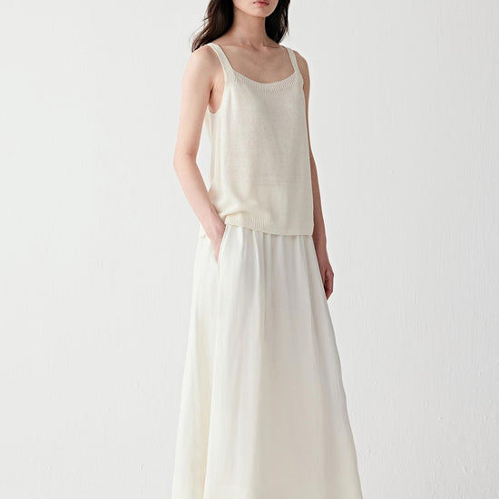 Video showing the model walking in a full light-toned outfit, emphasizing the fluid movement of the knit, breathability and soft drape over the body