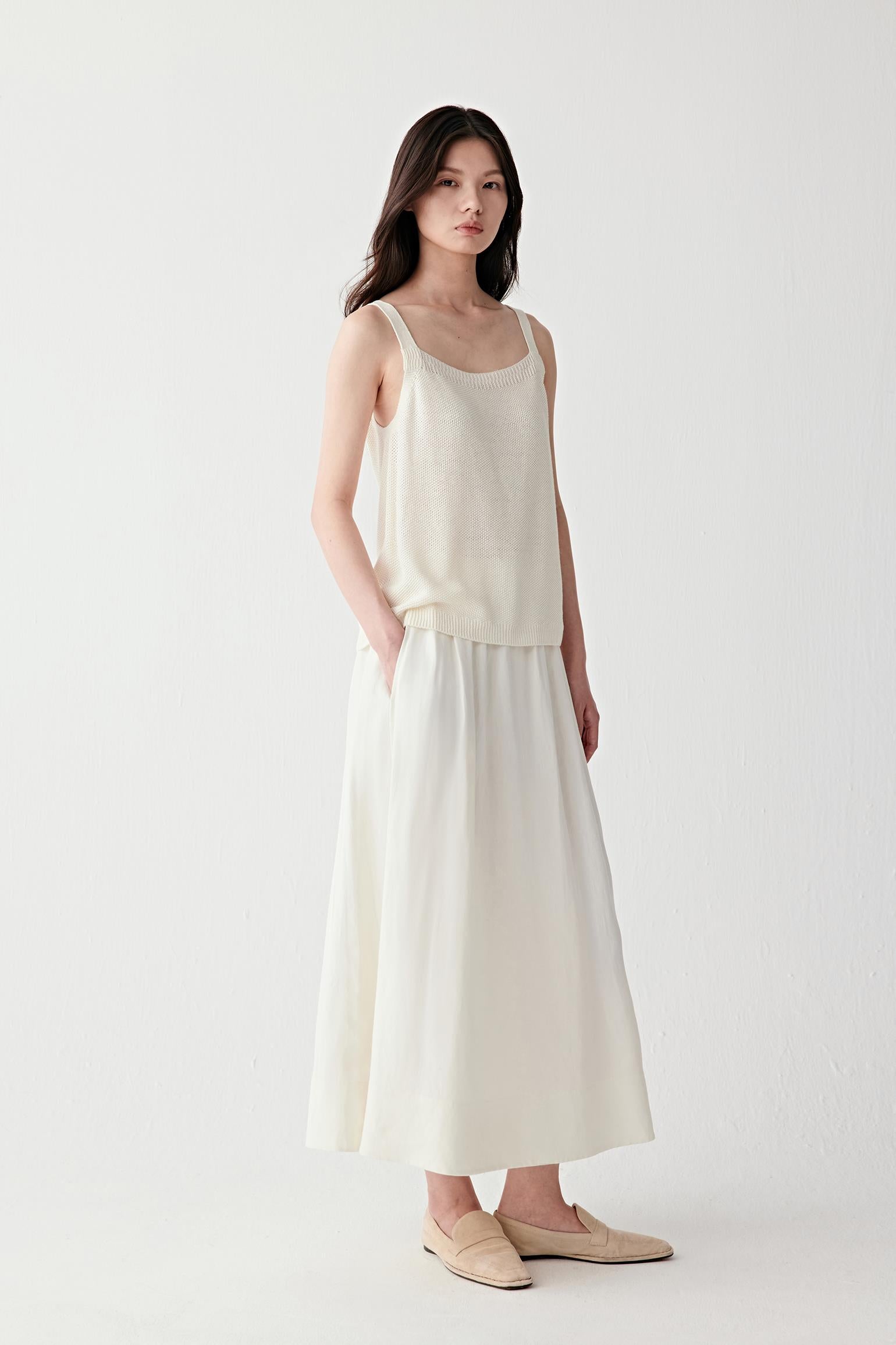 Video showing the model walking in a full light-toned outfit, emphasizing the fluid movement of the knit, breathability and soft drape over the body