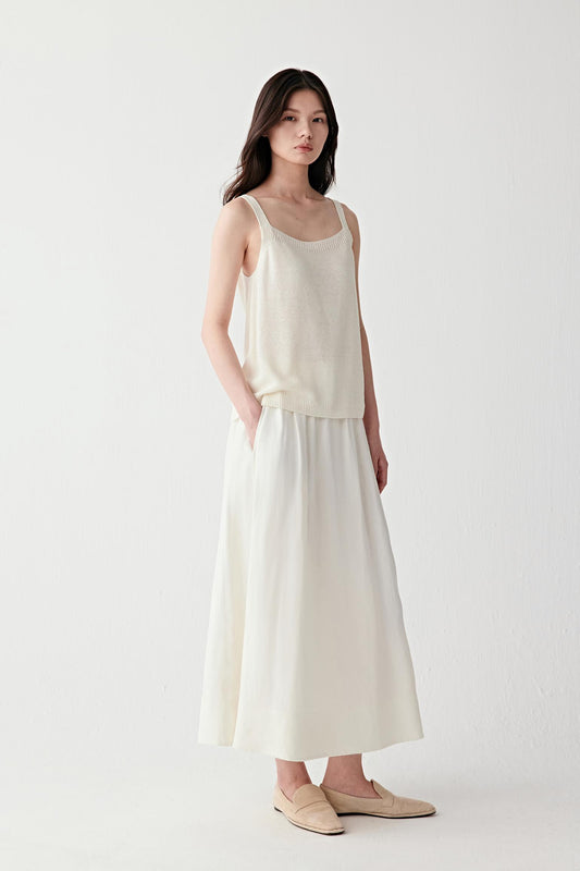 Video showing the model walking in a full light-toned outfit, emphasizing the fluid movement of the knit, breathability and soft drape over the body