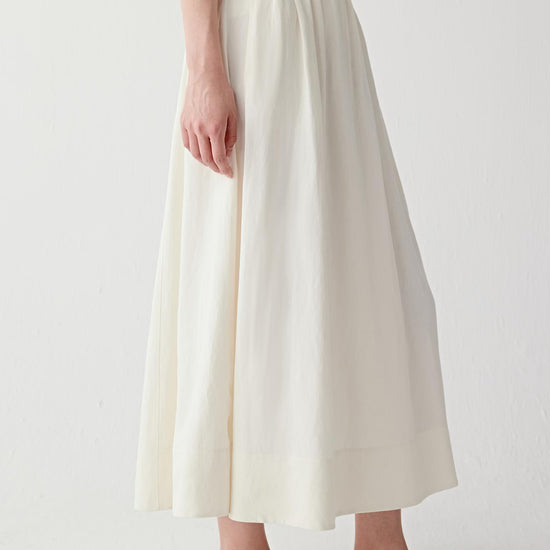 Video showing the model walking, highlighting the natural movement of the silk-linen fabric, the fluid expansion of the skirt and the light, breathable structure in motion