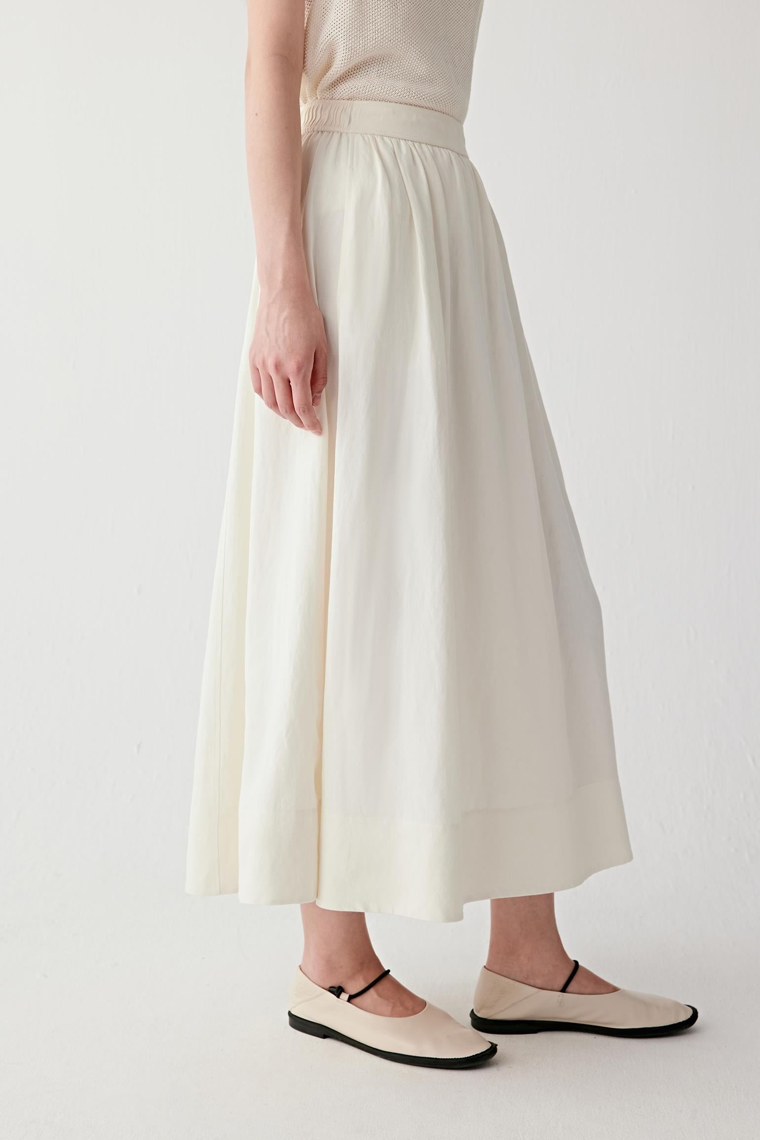 Video showing the model walking, highlighting the natural movement of the silk-linen fabric, the fluid expansion of the skirt and the light, breathable structure in motion
