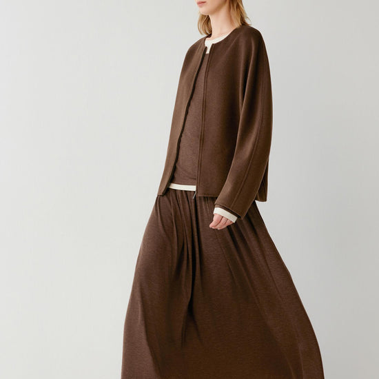 Video of a woman wearing a dark brown sleeveless coat in double-face yak and wool, showing the fluid movement of the long silhouette and the natural drape of the fabric as she walks.