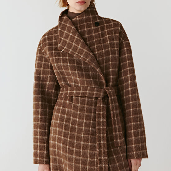 Product video showing a double-faced checked wool coat in natural brown tones, rotating to display the check pattern, collarless round neckline, raglan sleeves, welt pockets, and overall silhouette from all angles.