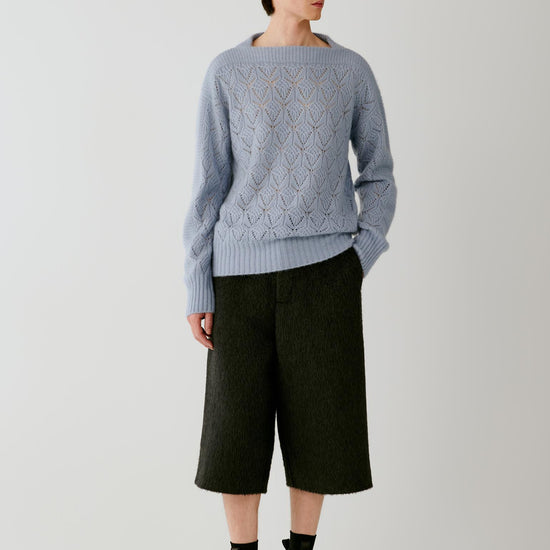 Video of a man wearing a light blue silk, cashmere and alpaca pullover, showing the relaxed silhouette and movement of the openwork knit as he moves.