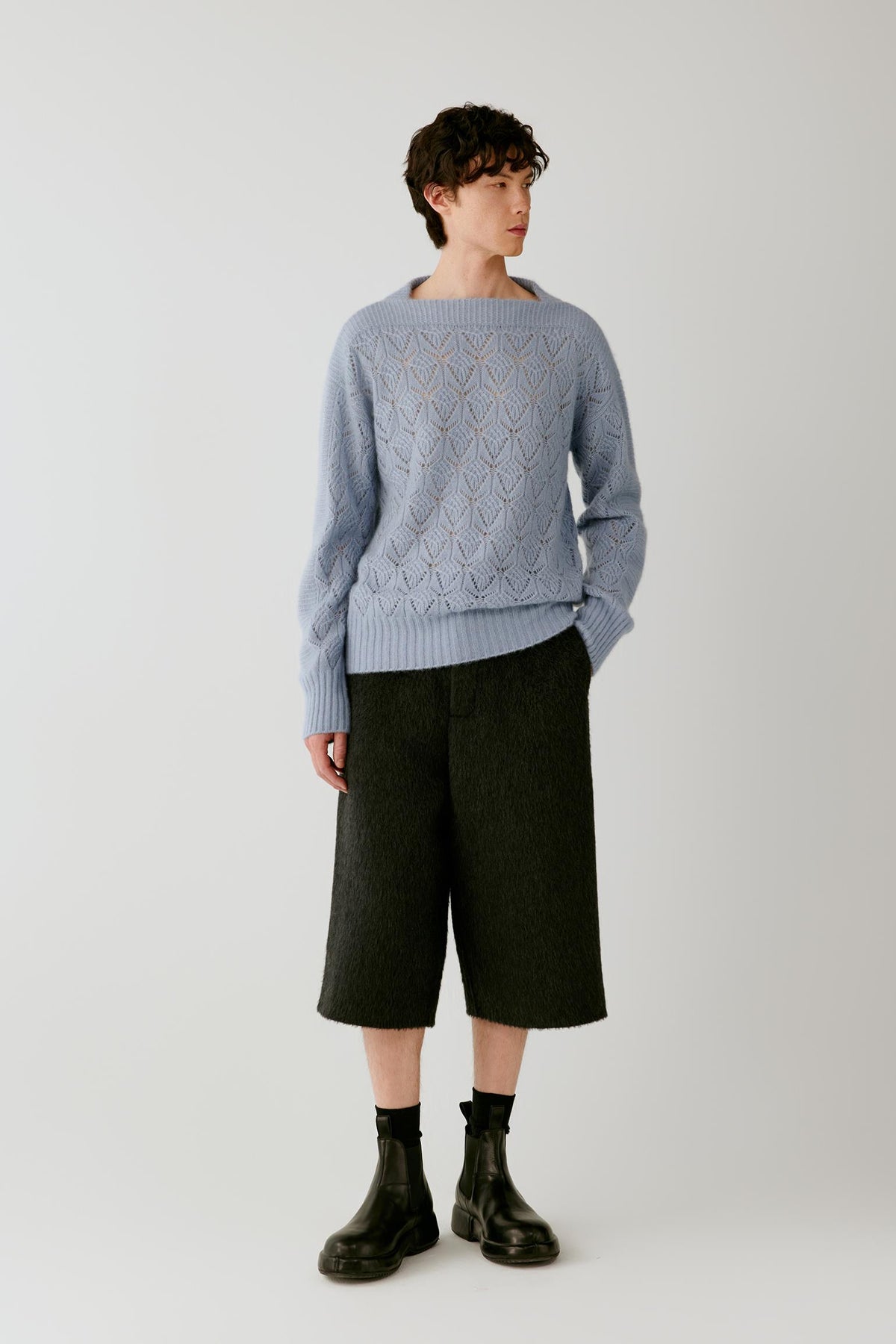 Video of a man wearing a light blue silk, cashmere and alpaca pullover, showing the relaxed silhouette and movement of the openwork knit as he moves.
