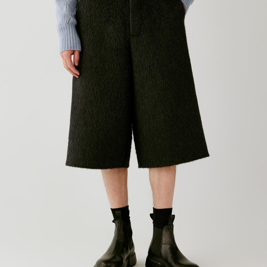 Video of a man wearing anthracite melange camel and mohair shorts, showing the wide below-the-knee silhouette and textured double-face fabric in movement.