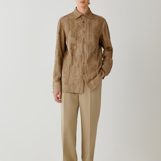Video of a man wearing a camel jacquard shirt, showing the relaxed silhouette and movement of the textured fabric as he moves.