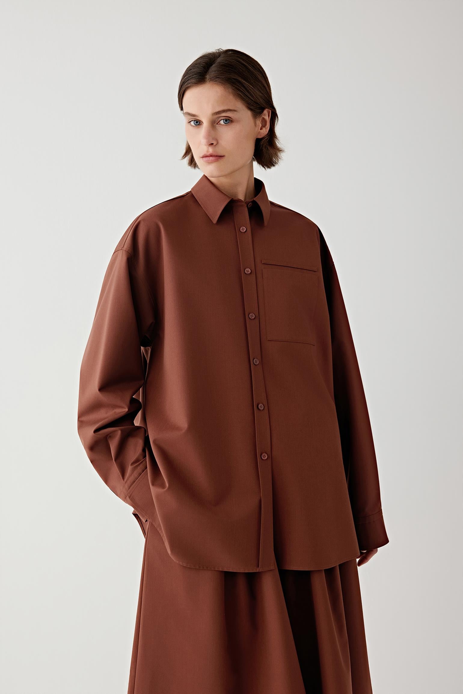 Woman wearing a brown shirt and brown skirt with a white background