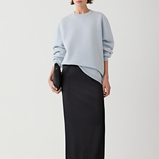 Video showing the model wearing the light blue pullover knitted from a blend of wool and cashmere while moving and walking in the studio. The sequence highlights the relaxed silhouette of the sweater, the smooth drape of the lightweight knit across the torso and sleeves, and the way the fabric moves naturally with the body. The round neckline sits close to the neck while the long sleeves follow the natural line of the arms.